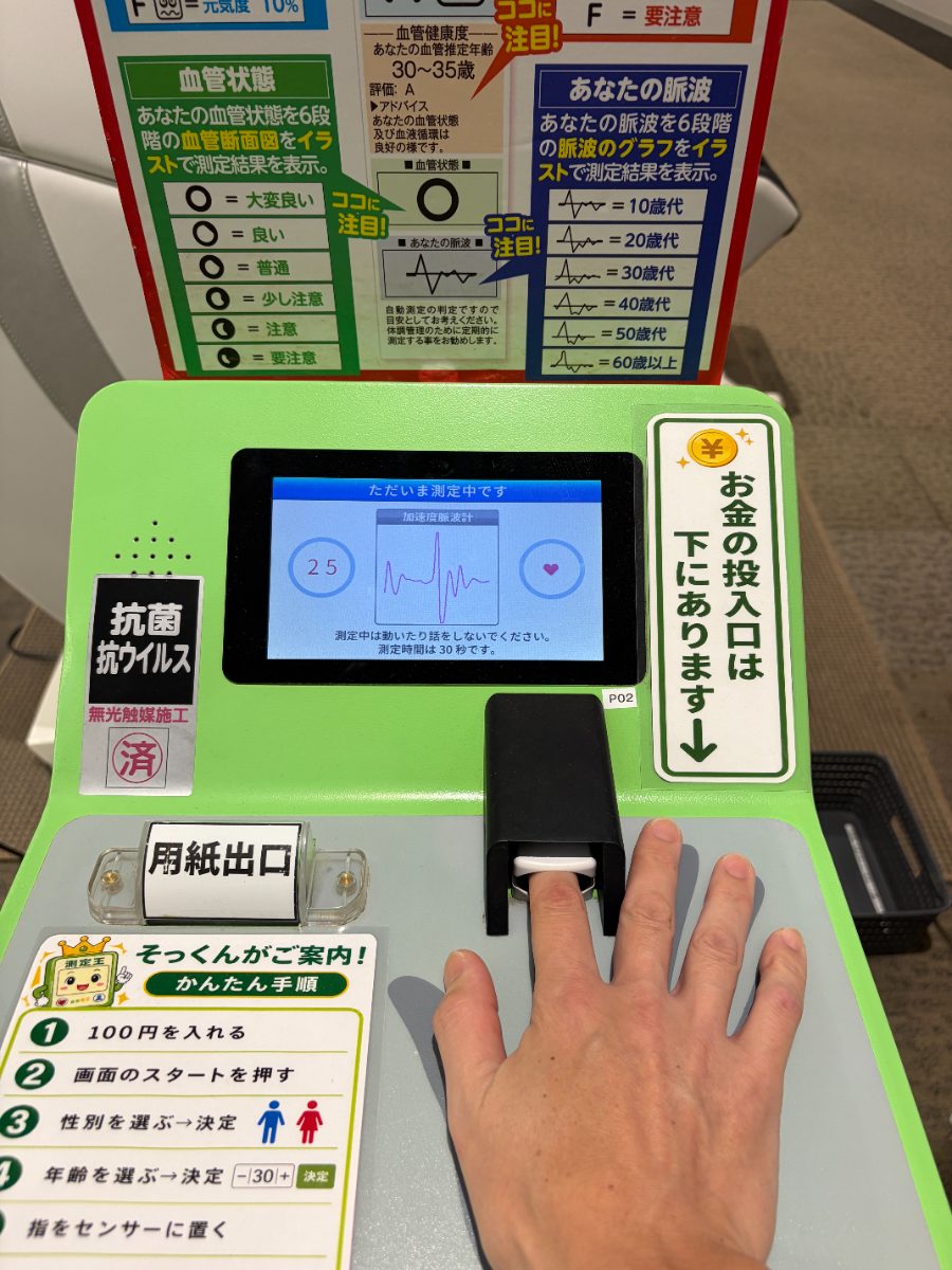 緑色の血管年齢測定器のセンサーに指を置いて測定しているところ