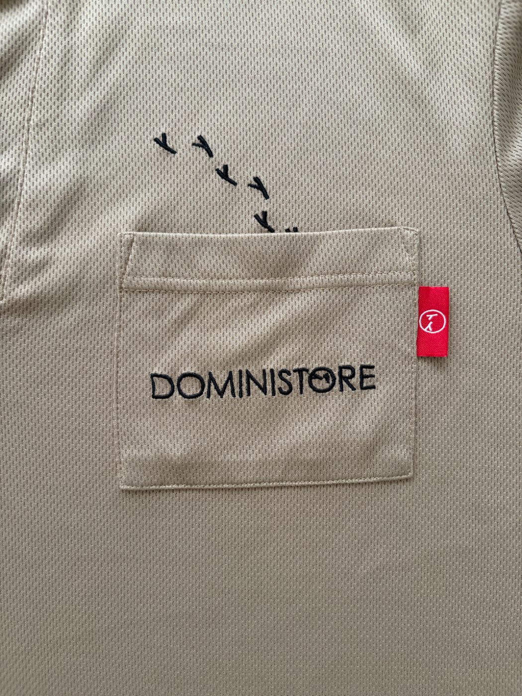 胸ポケットのDOMINISTOREの刺繍と赤いタグ
