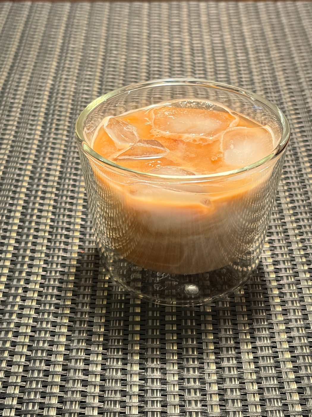 ガラスのグラスに入った、氷とミルクとエスプレッソの層が見えるアイスカフェラテ