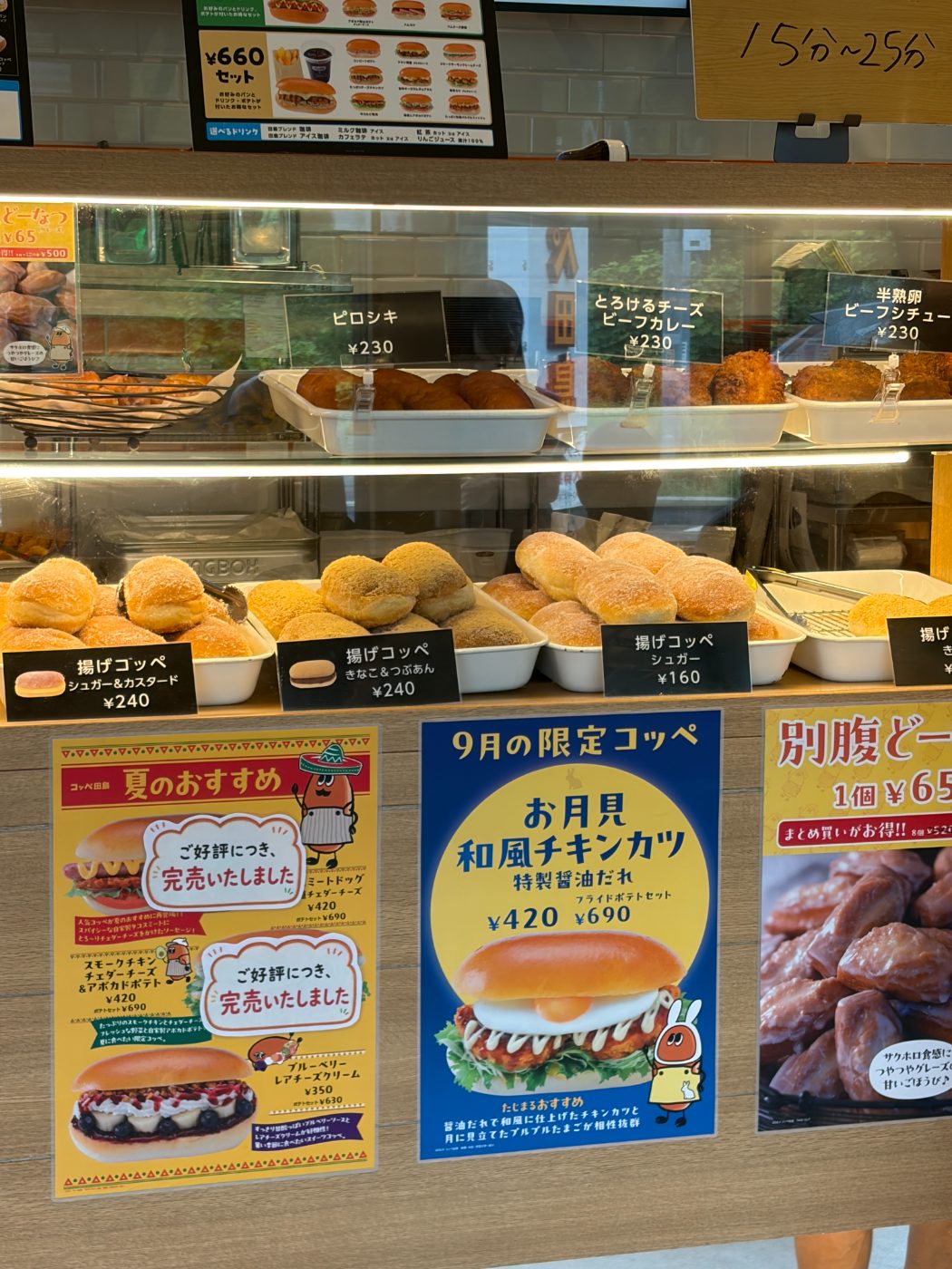 コッペ田島のショーケース。揚げコッペやピロシキが並び、上に15分〜25分と書かれた札が下がっている