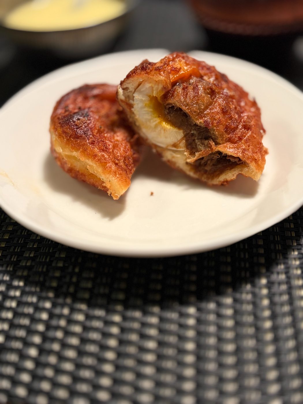 半分に割った半熟卵ビーフシチューのコッペパン。中から半熟卵と牛肉が見えている