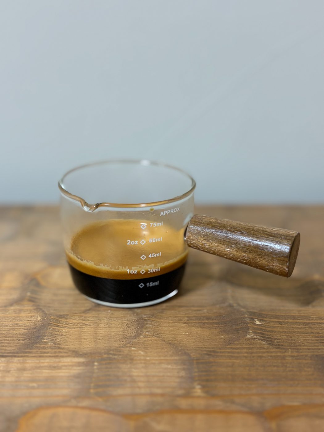 横から見た計量カップ。下の黒い液体の上に、分厚い茶色のクレマの層ができている