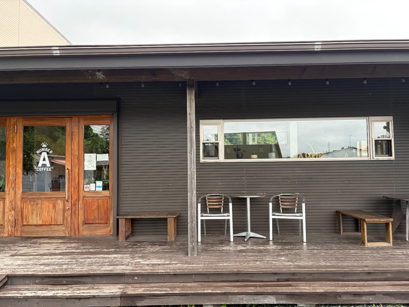 Number A Coffeeの外観。濃い茶色の板壁と木製の扉、外にベンチとテーブル席がある