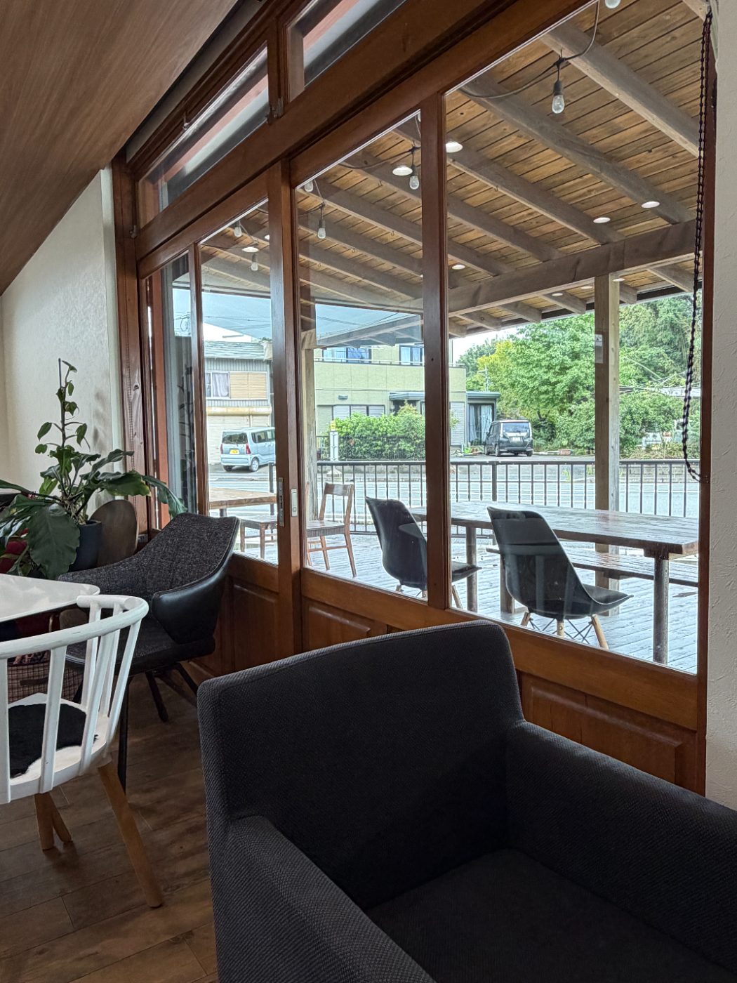 店内から見た大きな窓と外のテラス席。観葉植物とソファが置かれている