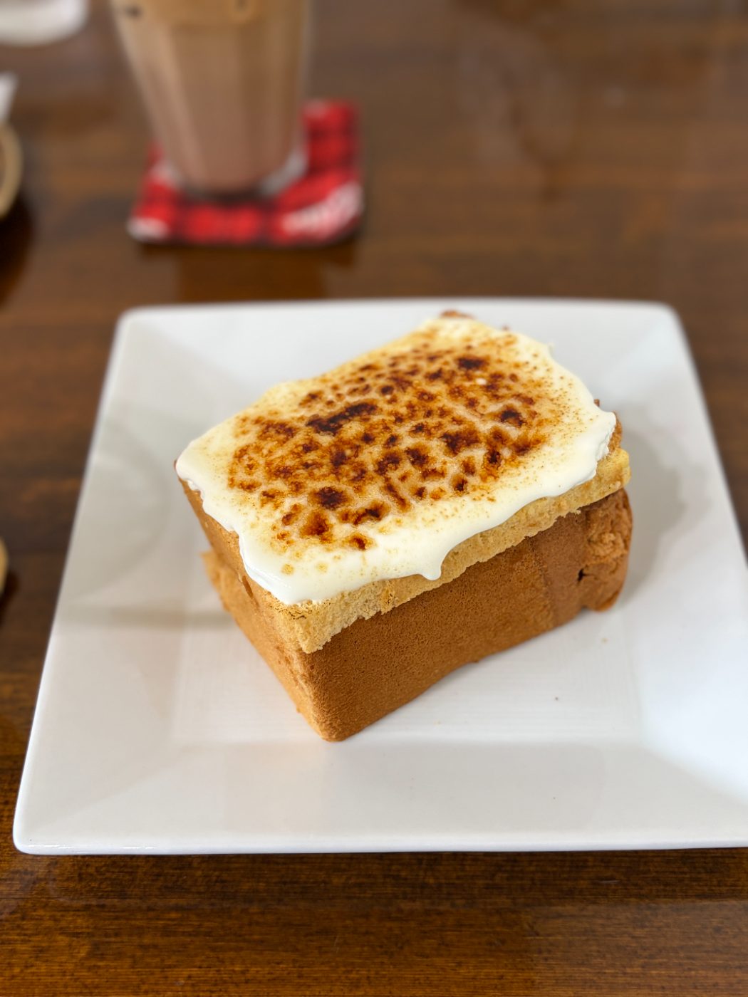 白い皿にのったブリュレシフォンケーキ。上面のクリームがバーナーで焦がされている