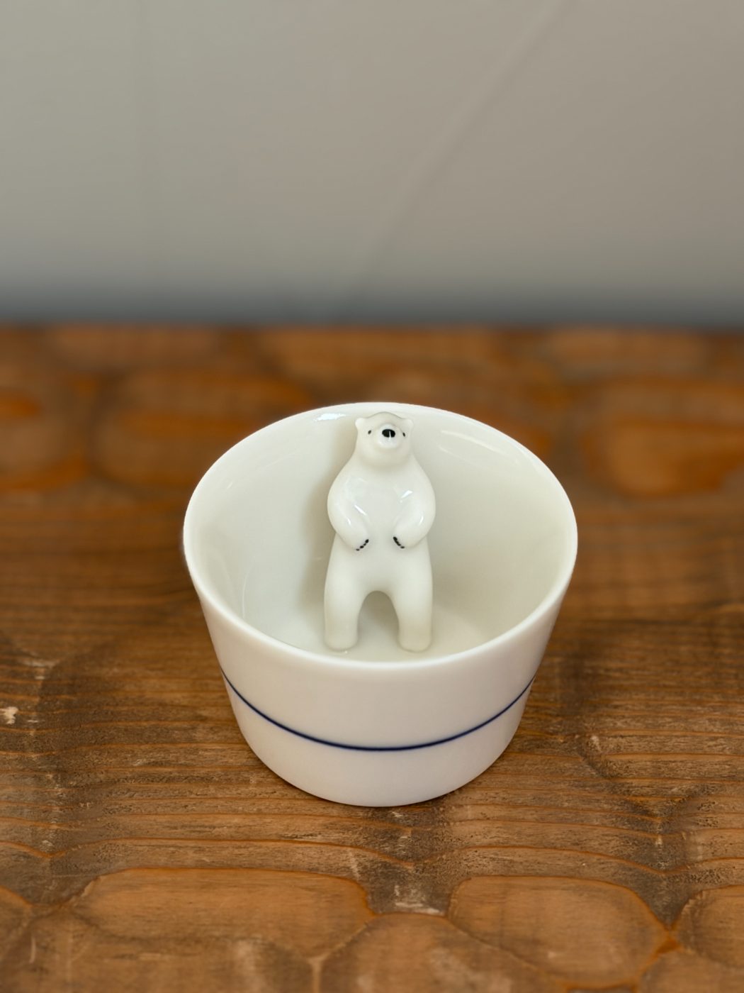 白いおちょこの内側に、シロクマが立って寄りかかっている。外側には青い線が一本