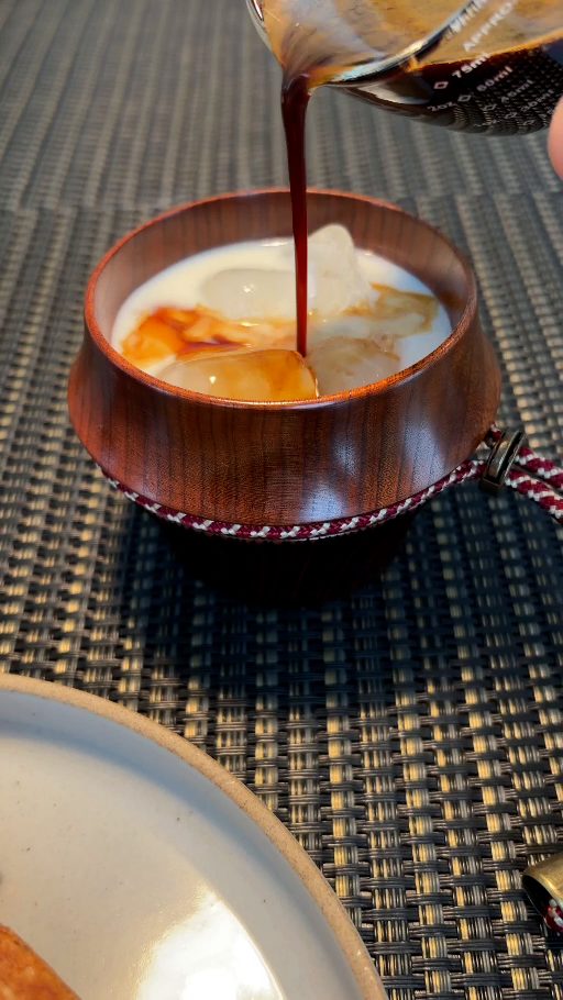 氷と牛乳の入った峰香に、ショットカップからエスプレッソを注いでいるところ