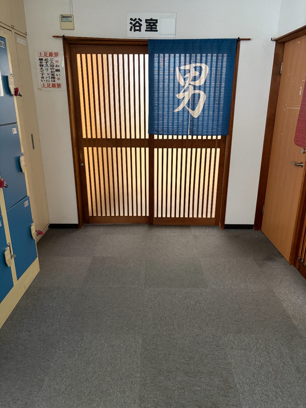 脱衣所から見た浴室の入口。男と書かれた青いのれんがかかっている